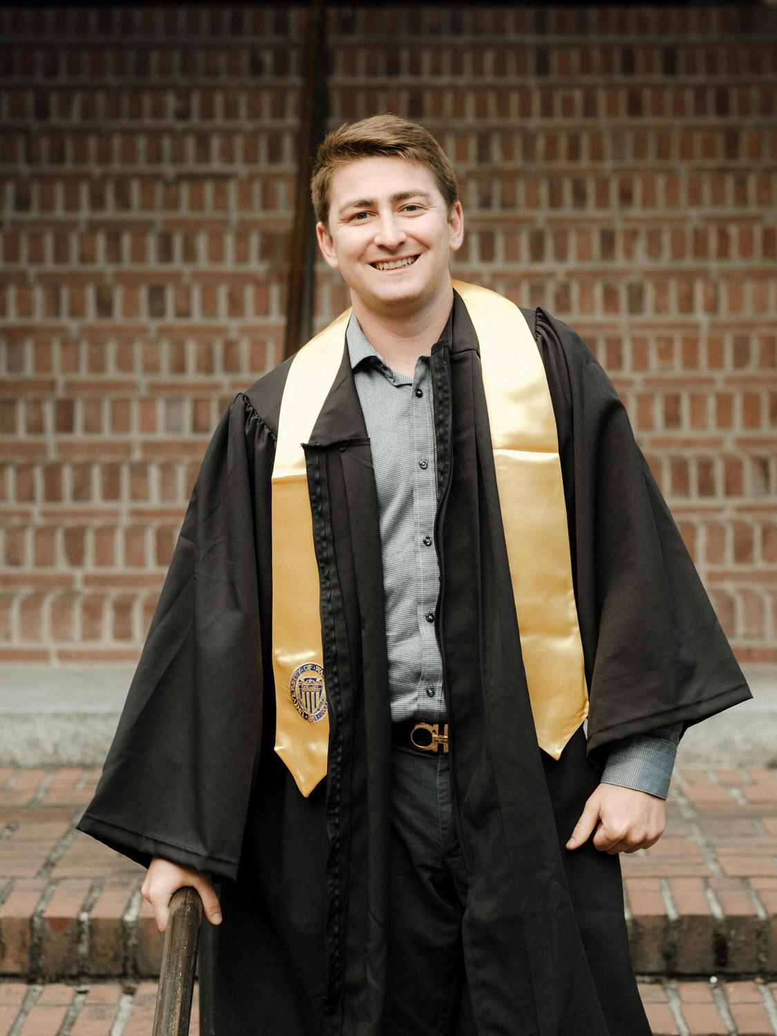 Portrait of UW graduate in his gown and yellow sash