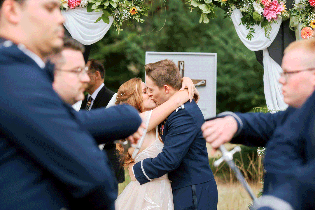 Bride and groom kiss while the groomsmen pull out their swords for the Arch of Sabers.