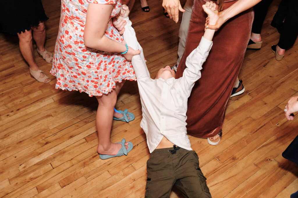 Young wedding guest is dragged across the dance floor