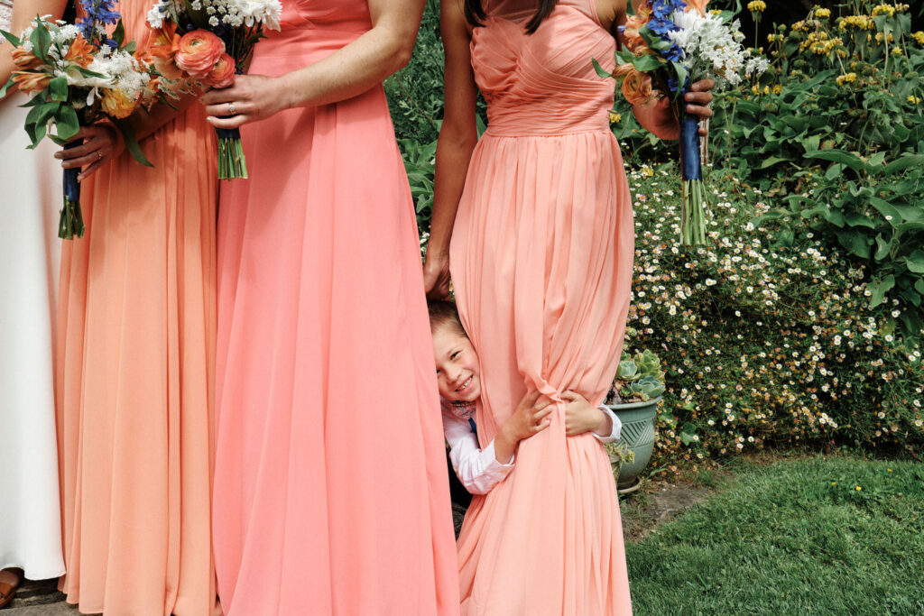 Bride's Nephew hides behind a bridesmaid dress at a Willow Camp Stinson Beach Wedding