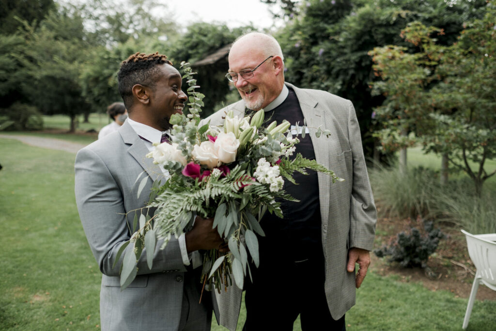 Wedding officiant laughs with one of the groomsmen