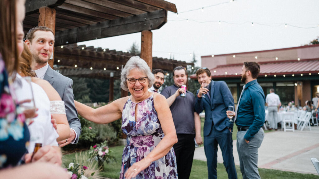 Wedding guest laughs while talking with the groom