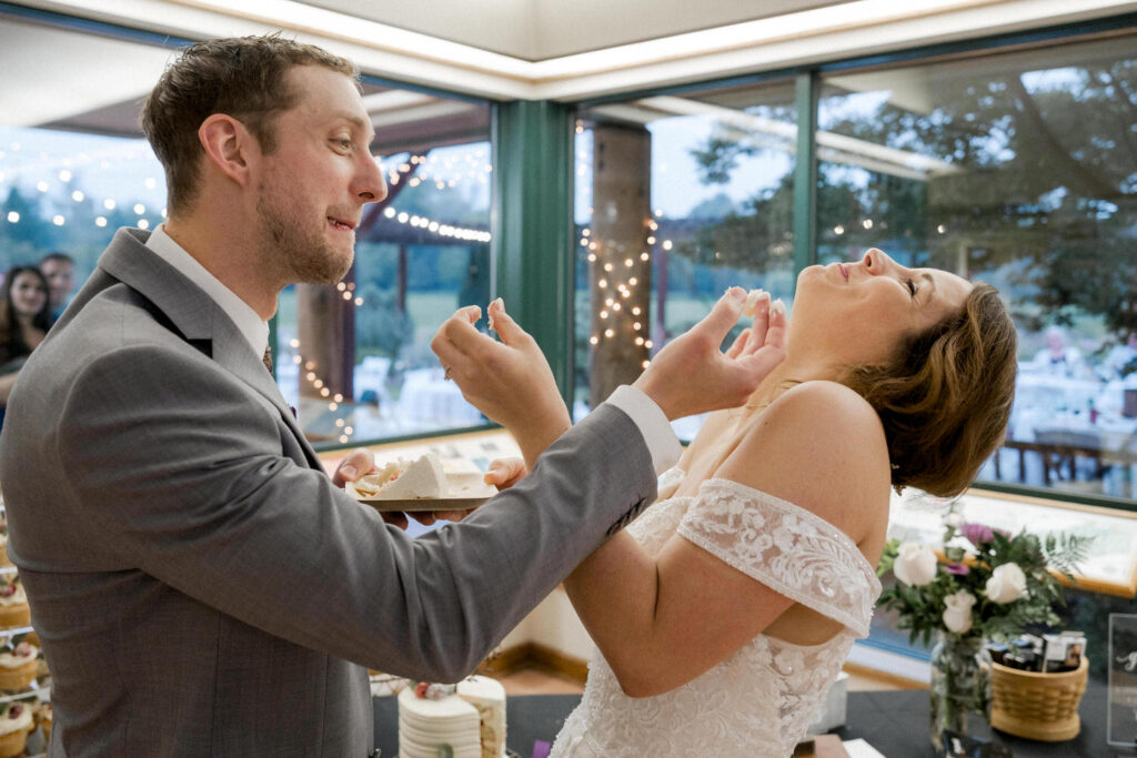 Bride laughs as the couple feeds each other the wedding cake