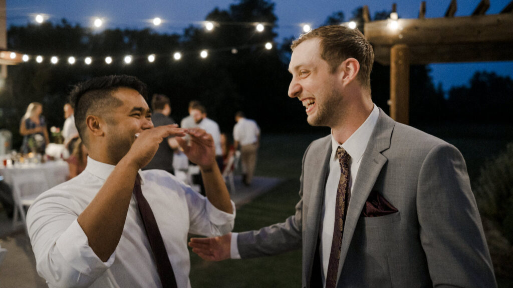Groom and wedding guest laugh after the garter toss