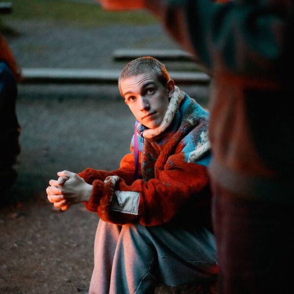 Olympic National Park Wedding | Sara and Robert's Summer Camp Wedding Weekend at NatureBridge 13 Guest in colorful fleece jacket sitting near firelight during outdoor welcome dinner at NatureBridge Olympic wedding
