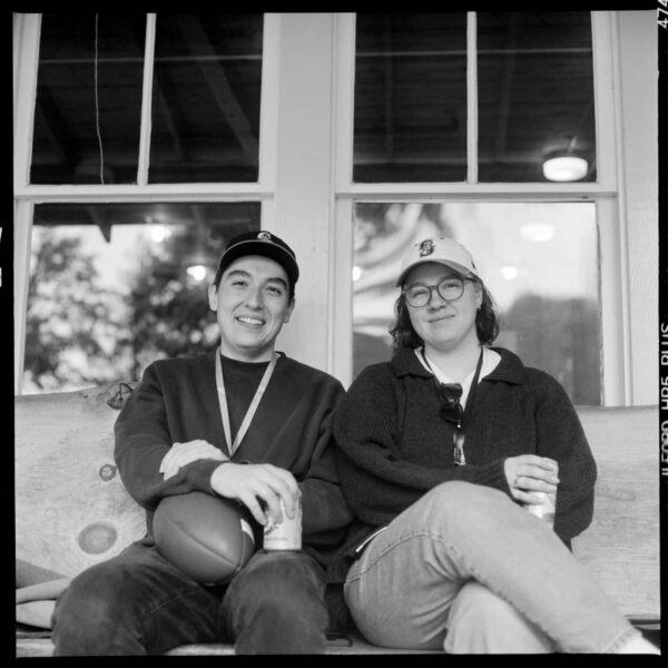 Olympic National Park Wedding | Sara and Robert's Summer Camp Wedding Weekend at NatureBridge 4 Wedding guests sitting together on a bench smiling during welcome dinner at NatureBridge Olympic in Olympic National Park