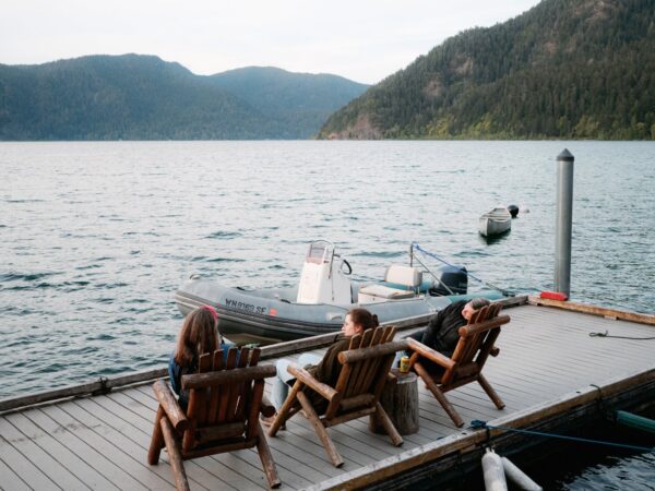 Olympic National Park Wedding | Sara and Robert's Summer Camp Wedding Weekend at NatureBridge 8 Guests relaxing in wooden chairs on dock overlooking lake at Olympic National Park wedding weekend
