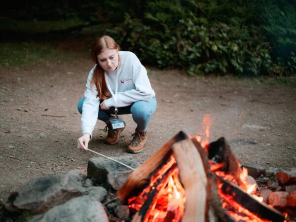 Olympic National Park Wedding | Sara and Robert's Summer Camp Wedding Weekend at NatureBridge 14 Guest roasting marshmallow during welcome dinner at NatureBridge Olympic summer camp wedding