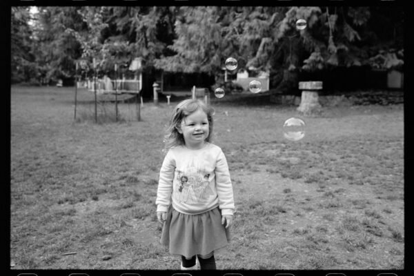 Olympic National Park Wedding | Sara and Robert's Summer Camp Wedding Weekend at NatureBridge 10 Child playing with bubbles on grassy field during Olympic National Park wedding weekend