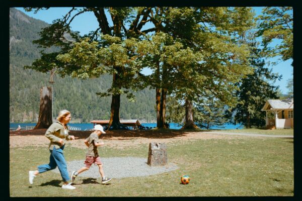 Olympic National Park Wedding | Sara and Robert's Summer Camp Wedding Weekend at NatureBridge 15 Wedding guests playing soccer on lawn beside lake during summer camp wedding weekend