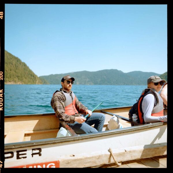 Olympic National Park Wedding | Sara and Robert's Summer Camp Wedding Weekend at NatureBridge 16 Wedding guest seated in canoe on mountain lake during Olympic National Park wedding weekend