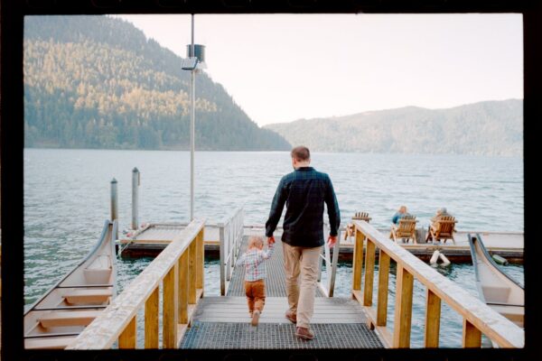 Olympic National Park Wedding | Sara and Robert's Summer Camp Wedding Weekend at NatureBridge 33 Parent and child walking down dock toward lake during summer camp wedding weekend