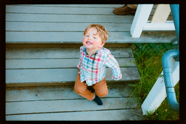 Olympic National Park Wedding | Sara and Robert's Summer Camp Wedding Weekend at NatureBridge 42 Child smiling on cabin steps during family-friendly summer camp wedding weekend