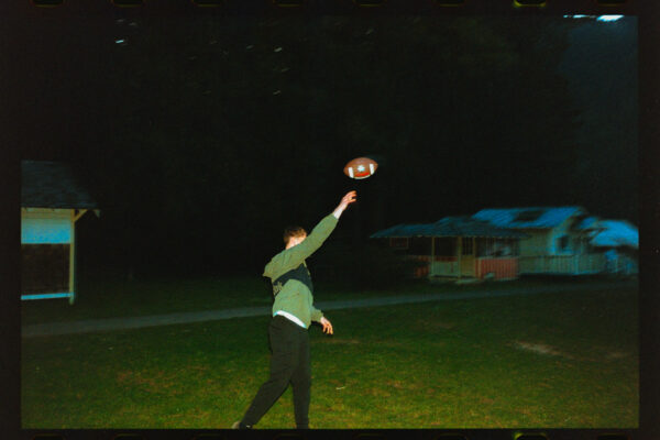 Olympic National Park Wedding | Sara and Robert's Summer Camp Wedding Weekend at NatureBridge 54 Wedding guest throwing football on lawn at night during camp wedding celebration