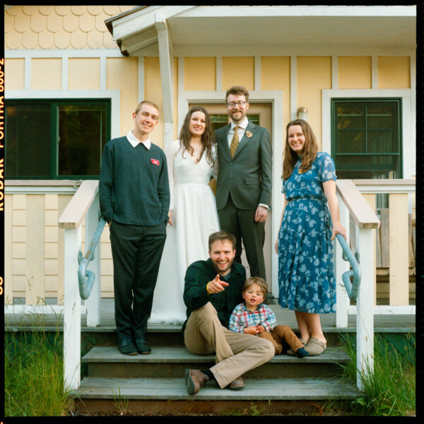 Olympic National Park Wedding | Sara and Robert's Summer Camp Wedding Weekend at NatureBridge 43 Bride and groom posing with family on cabin steps during intimate wedding weekend