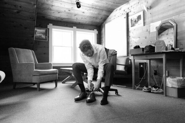 Olympic National Park Wedding | Sara and Robert's Summer Camp Wedding Weekend at NatureBridge 19 Groom getting ready and tying shoes inside cabin before outdoor wedding ceremony