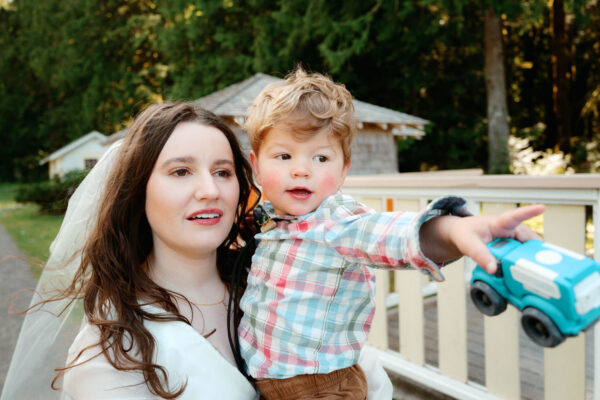 Olympic National Park Wedding | Sara and Robert's Summer Camp Wedding Weekend at NatureBridge 25 Bride holding child during candid family moment at summer camp wedding