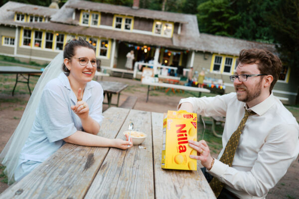 Olympic National Park Wedding | Sara and Robert's Summer Camp Wedding Weekend at NatureBridge 51 Bride and groom eating late night snacks at picnic table outside reception lodge