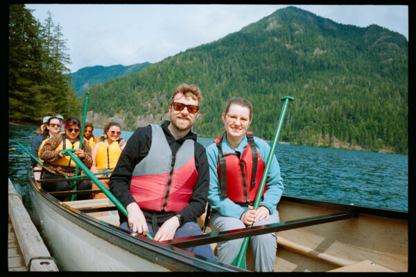 Olympic National Park Wedding | Sara and Robert's Summer Camp Wedding Weekend at NatureBridge 56 Bride and groom seated together in canoe on Lake Crescent during wedding weekend excursion