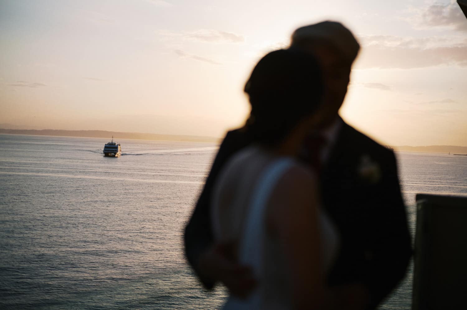 The Edgewater Hotel Wedding | Candid Seattle Wedding Photography for Amy & Mike 25 Silhouette of the couple at sunset with a ferry crossing Puget Sound outside the Edgewater Hotel in Seattle